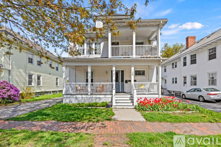 A two-story house with a porch and a car parked in front.