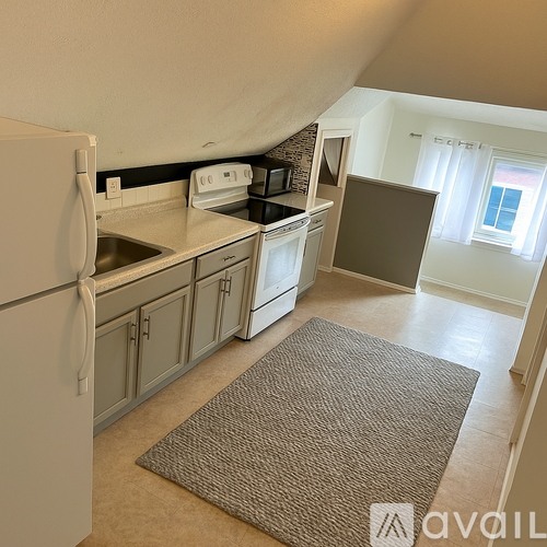 A kitchen with a white refrigerator and a brown rug on the floor.