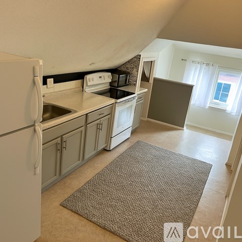 A kitchen with a white refrigerator and a brown rug on the floor.