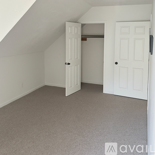 A room with a carpeted floor and two white doors.
