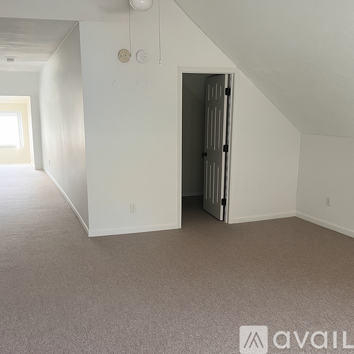 A room with a carpeted floor and a door on the right side.