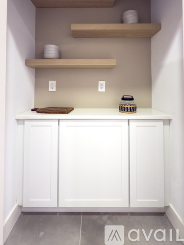 A kitchen with white cabinets and wooden shelves above.