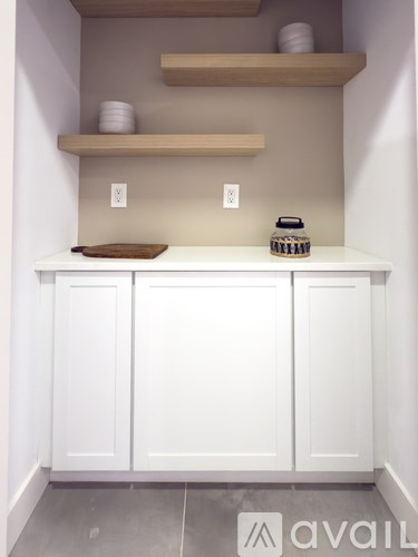 A kitchen with white cabinets and wooden shelves above.