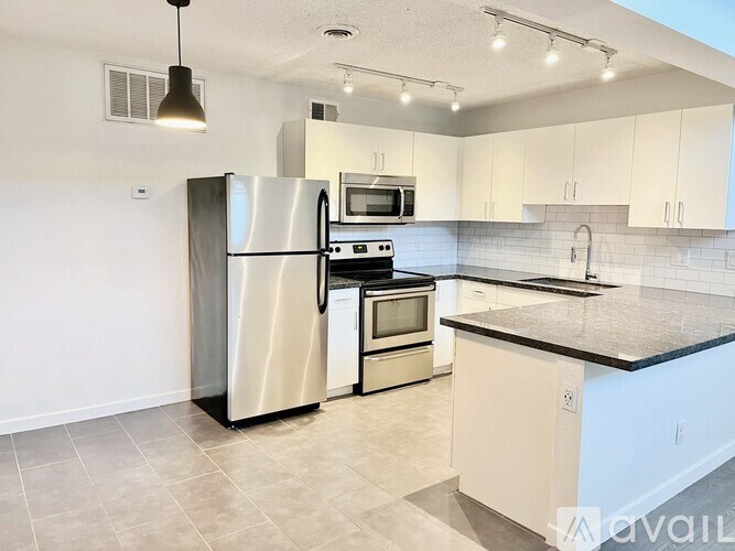 A modern kitchen with a stainless steel refrigerator, microwave, oven, and sink.