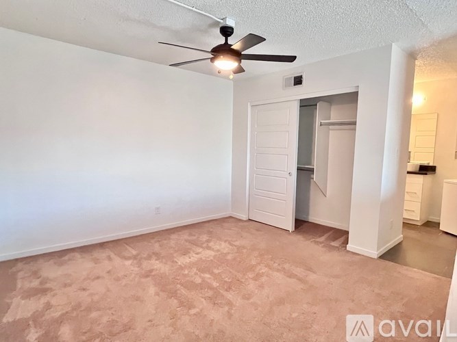 A room with a ceiling fan and carpeted floor.