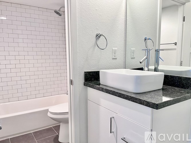 A white bathroom with a black counter top and a white sink.