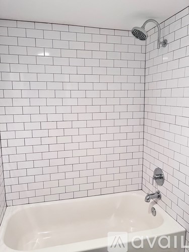 A white bathtub with a shower head and faucet.