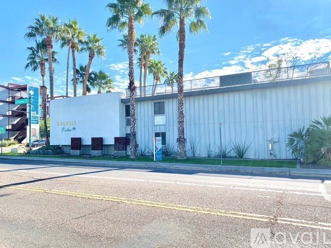 A white building with palm trees in front of it.
