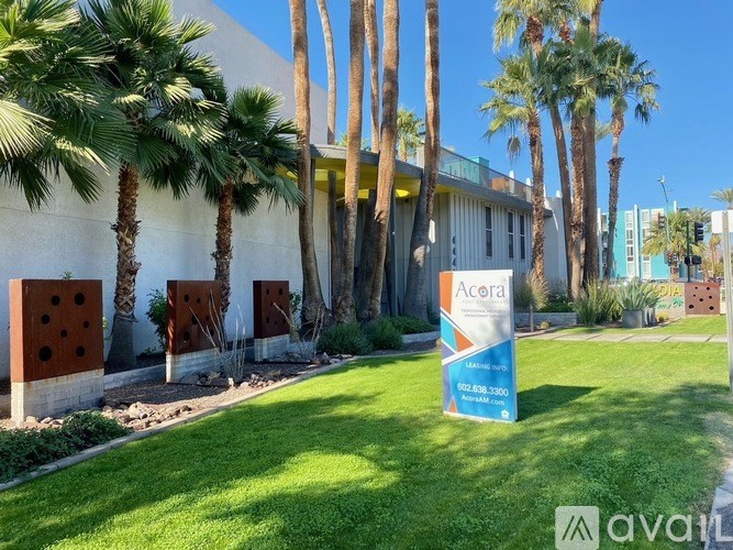 A sign for Acura is in front of a building with palm trees.