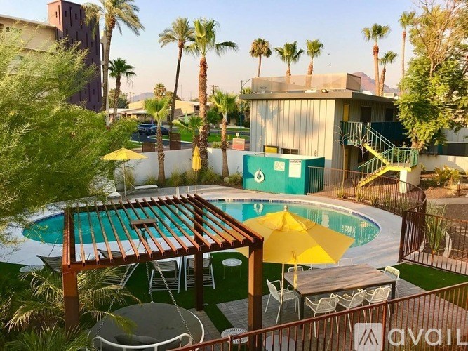 A pool with a wooden deck and yellow umbrella.