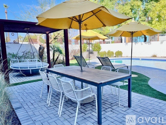 A patio with a table, chairs, and umbrellas.