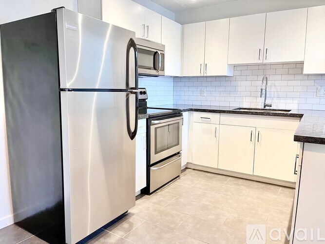 A kitchen with a stainless steel refrigerator and white cabinets.