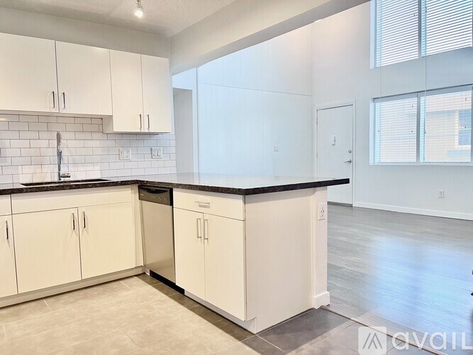 A kitchen with white cabinets and a black countertop.