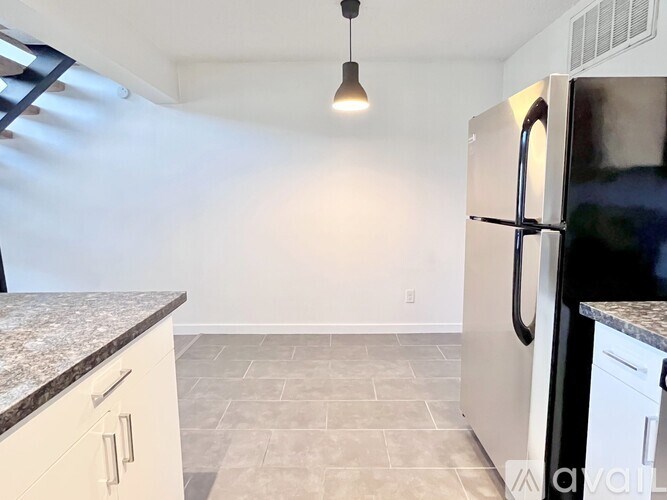 A kitchen with a granite countertop and a stainless steel refrigerator.