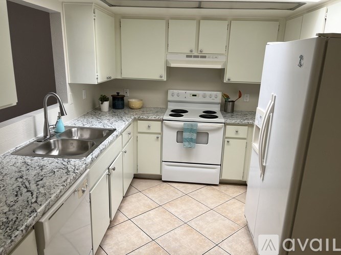 A kitchen with white appliances and a marble countertop.