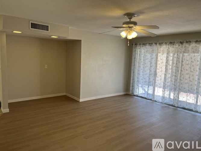 A room with a ceiling fan and a window with curtains.