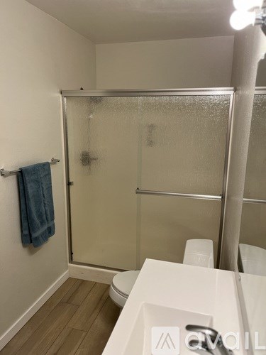 A small bathroom with a toilet, sink, and shower.