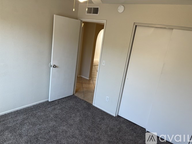 A room with a white door and a grey carpet.