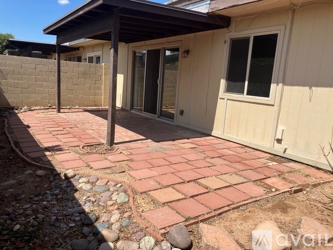 A patio area with a brick walkway and a small building with a door and windows.