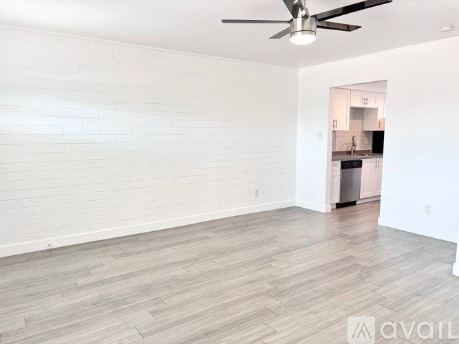 A room with a ceiling fan and wooden flooring.
