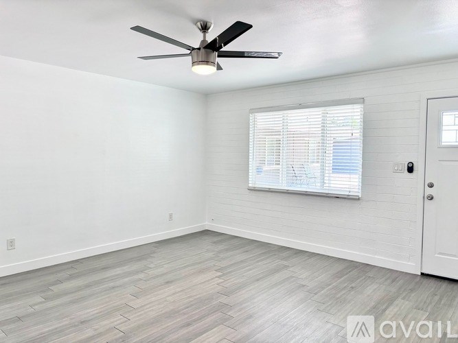 A room with a ceiling fan and a window with blinds.