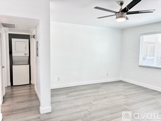A spacious room with a ceiling fan and a door leading to a kitchen.