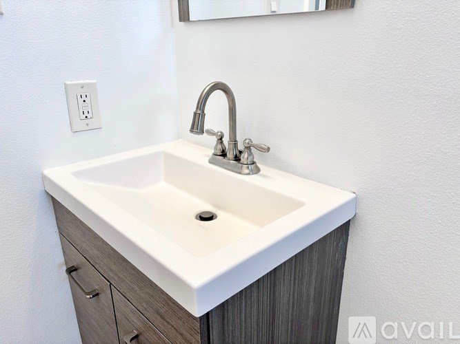 A white sink with a silver faucet is mounted on a wooden cabinet.