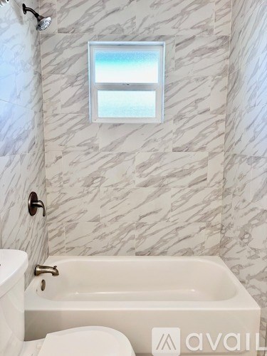 A bathroom with a tub, toilet and a window.