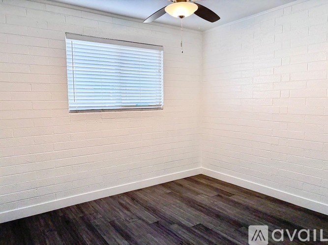 A room with a ceiling fan and a window with blinds.