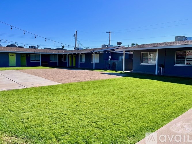 A sunny day at a blue house with a green lawn.