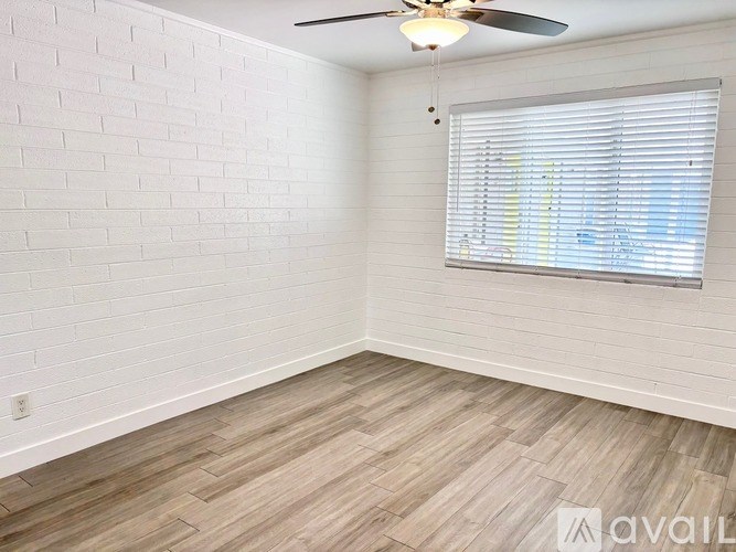 A room with a ceiling fan and a window with blinds.