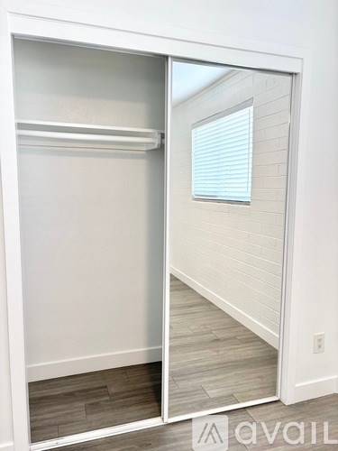 A white closet with a mirror and a window.