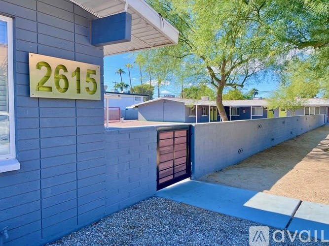 A house numbered 2615 with a brown door and a tree in the background.