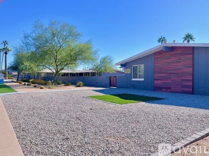 A house with a red garage door and a gravel driveway.
