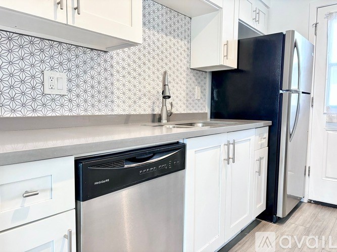 A kitchen with a black fridge and a dishwasher.