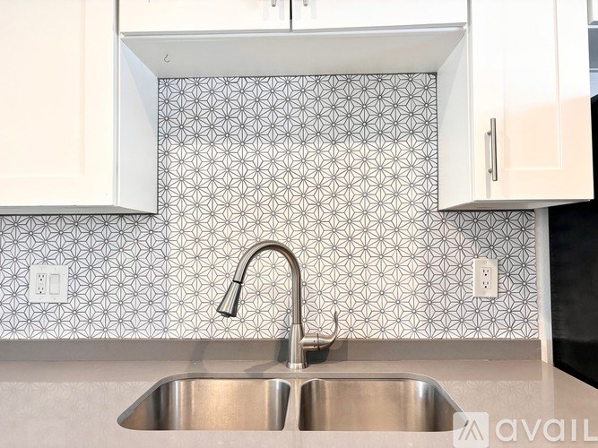 A kitchen with a patterned backsplash and a stainless steel sink.
