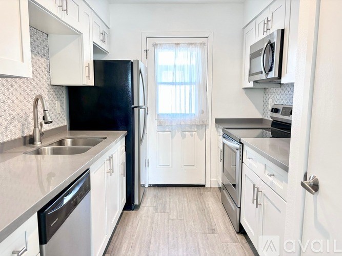 A kitchen with white cabinets and a black refrigerator.
