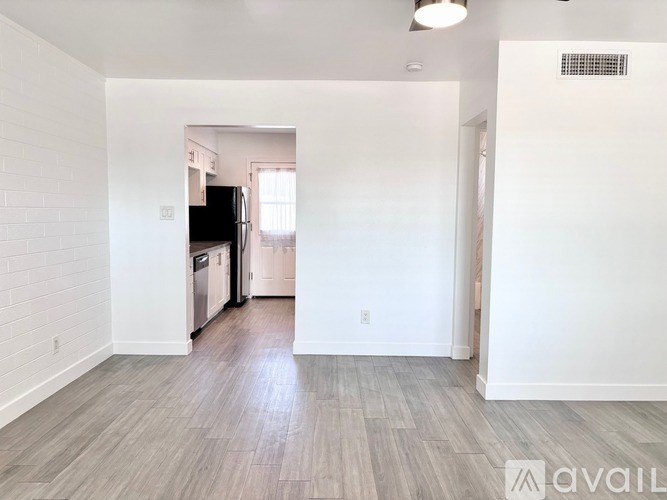 A spacious kitchen with white walls and wooden flooring.