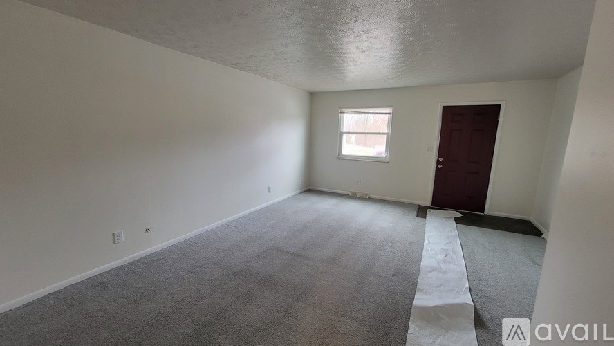 A room with a carpeted floor, a window, and a door.