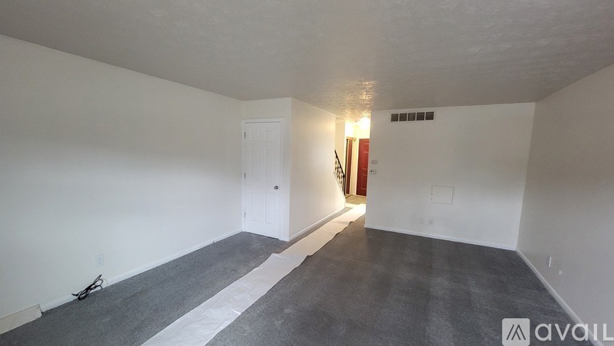 A room with a white door and a grey carpet.