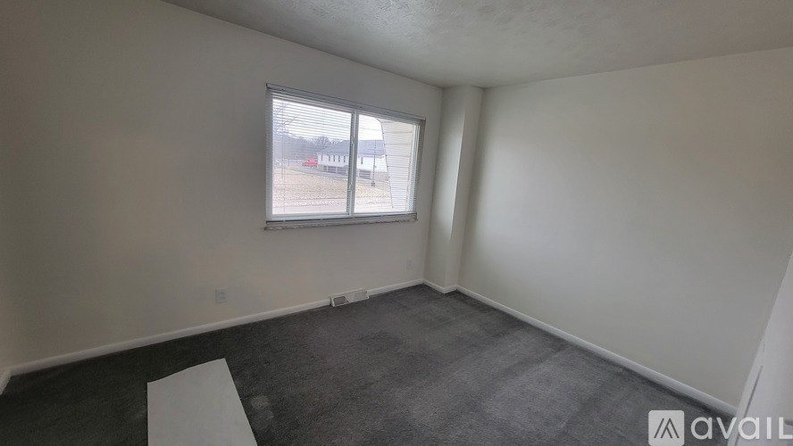 A room with a window and a view of a parking lot.