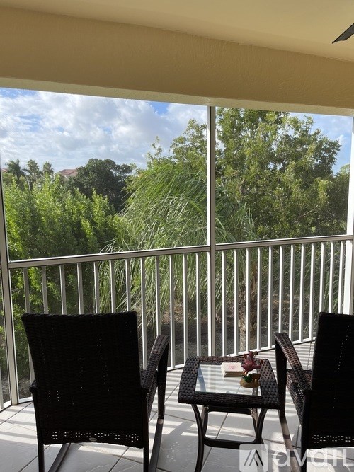 A balcony with two chairs and a table with a book on it.