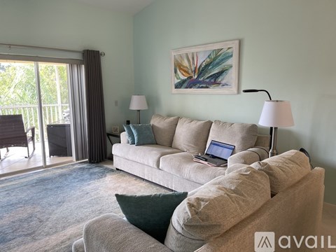 A living room with a couch, a laptop on it, and a painting on the wall.