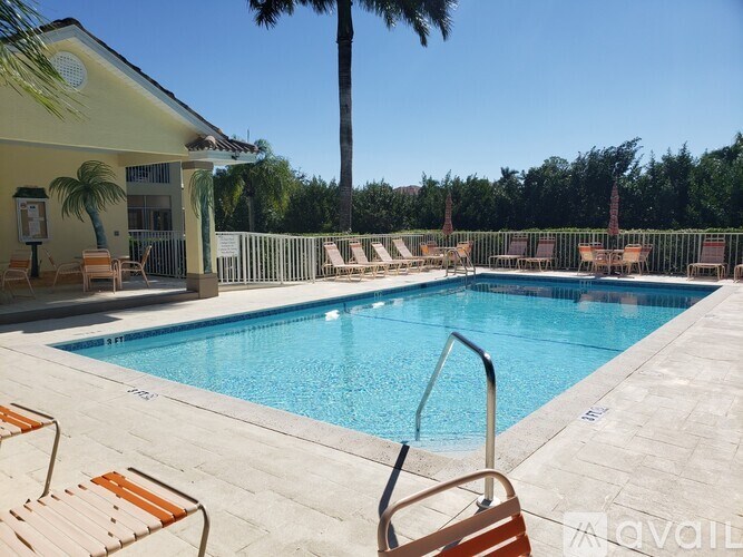 A pool with a chair and a house in the background.