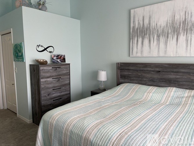 A bedroom with a bed, nightstand, and a painting on the wall.