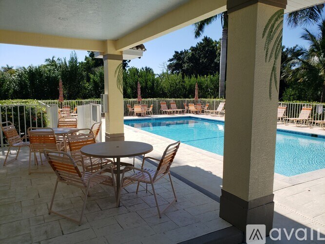 A patio with a table and chairs overlooking a pool.