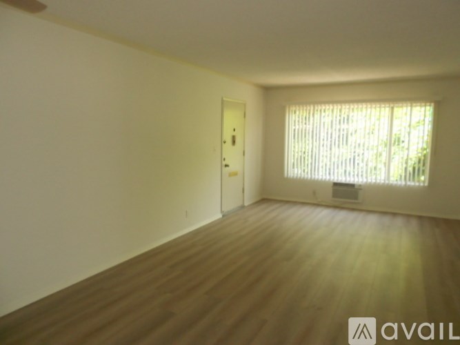 A room with a wooden floor and a window with blinds.