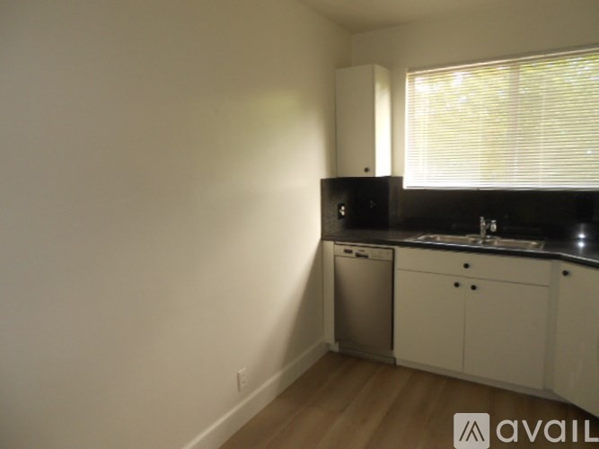 A kitchen with white cabinets and a black countertop.