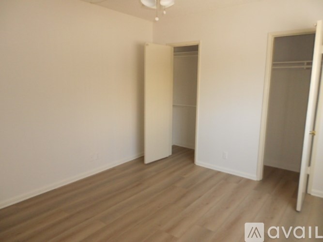 A room with wooden floors and white walls, with a door on the right side.