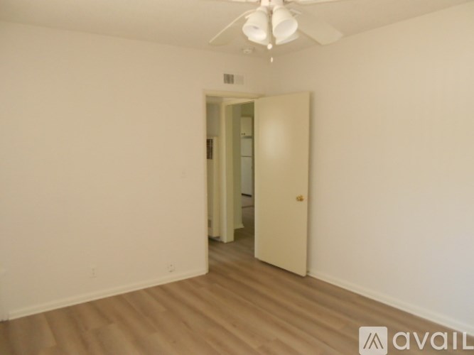 A room with a white ceiling fan and a doorway leading to another room.